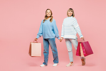 Full body elder parent mom young adult daughter two women together wear blue casual clothes hold paper package bags after shopping isolated on plain pink background Black Friday sale buy day concept.