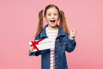 Little child cute kid girl 7-8 year old wear denim shirt hold store gift certificate coupon voucher card do winner gesture isolated on plain pink background. Mother's Day love family lifestyle concept - obrazy, fototapety, plakaty