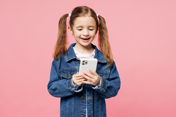 Little child happy cute kid girl 7-8 years old wears denim shirt have fun hold in hand use mobile cell phone isolated on plain pastel light pink background. Mother's Day love family lifestyle concept.