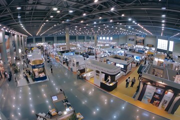 Wide-Angle View of Busy Exhibition Hall with Colorful Booths - obrazy, fototapety, plakaty