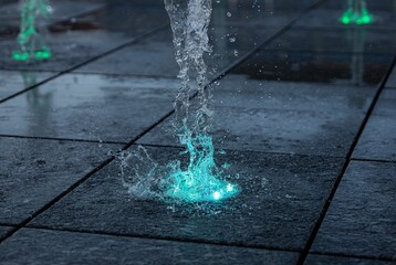 Closeup shot of a fountain illuminated by vibrant green lights spouting water