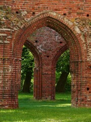 Arched brick entryway to the Eldena Monastery on a lush, verdant grassland