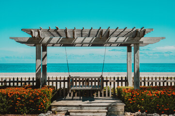 Lush garden with a picket fence, situated on a beachfront property, overlooking the blue water