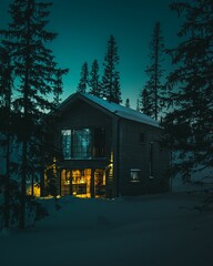 Picturesque winter scene featuring a wooden cabin nestled amongst evergreen trees.