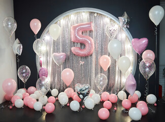 A photo zone of white and pink balloons with the number five. A little girl's birthday - 769700301