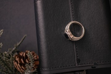 Closeup of a ring and a pinecone on a leather flask