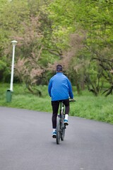 Fototapeta premium Young adult cyclist leisurely riding a bicycle down a rural road surrounded by trees