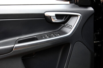 Driver door trim. Window control buttons in modern SUV. Car leather interior details of door handle...