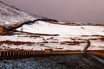 Scenic view of a fence on a mountain range covered with snow in winter in the countryside