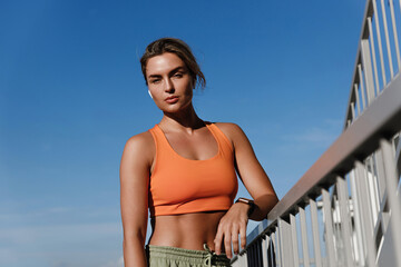 Young Woman Fitness Enthusiast Wearing an Orange Sports Bra Resting Outdoors