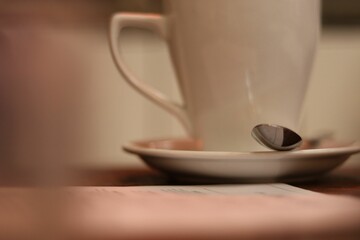a spoon and a cup are on the table next to some books