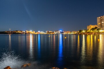 Scenic shot of a city skyline reflected in the tranquil waters of the sea in Mallorca, Spain