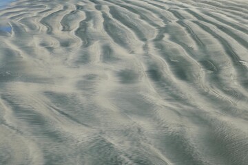 Aerial view of a pristine sandy beach with grayish-white sand