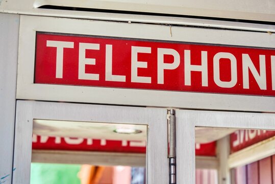 Closeup of a red sign on a telephone booth outdoors