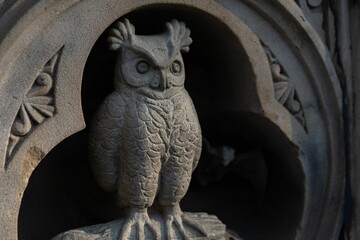 Intricately carved owl sculpture perched atop a circular stone structure in central park, new york