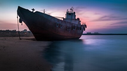 Antiquated vessel docked at the beach at sunset