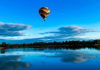 Vibrant colorful hot air balloon hovering over a tranquil lake