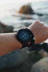 Close-up of a modern sports watch on the wrist of a man against a beach backdrop