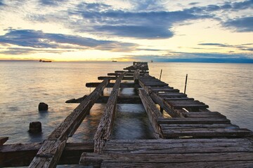 Scenic view of a wooden pier reaching out to the horizon at sunrise in Punta Arenas, Chile