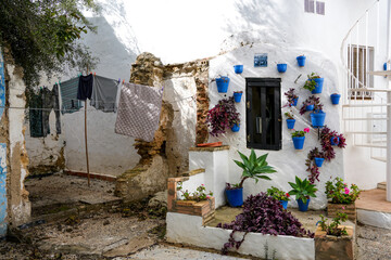 White andalusian patio with blue pot and red flowers, old well bucket inside a window,line drying...