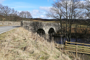 Fototapeta na wymiar An old stone bridge crossing the River Almond at Newton, Perth and Kinross, Scotland, UK.
