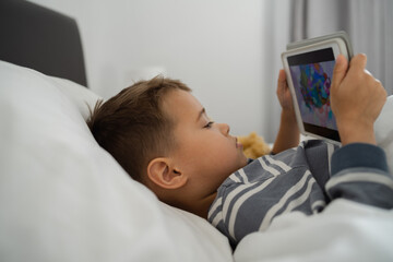  Toddler Boy Engrossed in Tablet Technology in Bed