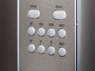 Closeup of an appliance control panel buttons on a metal surface