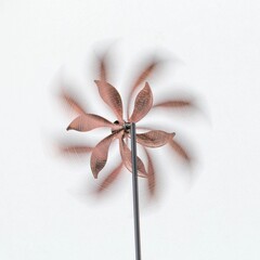 Vibrant pink metal wind spinner suspended in front of a stark white background