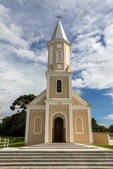 Fototapeta na wymiar Grand, white and tan colored church on top of a lush, green hill