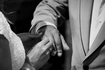 Close-up shot of a newlywed couple putting rings on hands at a wedding ceremony