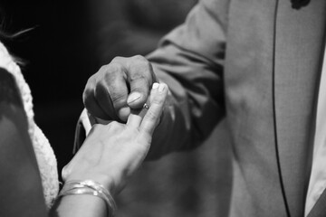 Close-up shot of a newlywed couple putting rings on hands at a wedding ceremony