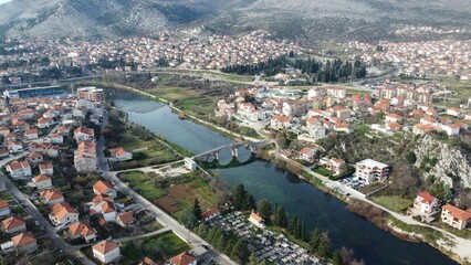 Naklejka premium Scenic view of a cityscape featuring a river with a bridge, against a backdrop of city buildings