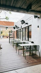 a wood covered patio with several black chairs and tables with wooden flooring