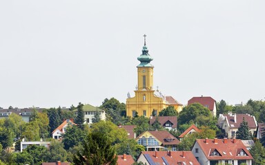 Aerial view of a cityscape featuring a historic yellow church in Veszprem, Hungary