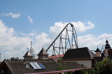 an amusement park has roller coaster and houses in the background