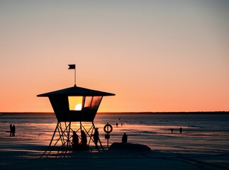 a life guard tower sitting on top of the beach in the sunset