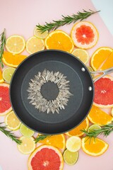 Stainless steel frying pan with sunflower seeds and freshly cut citrus and rosemary