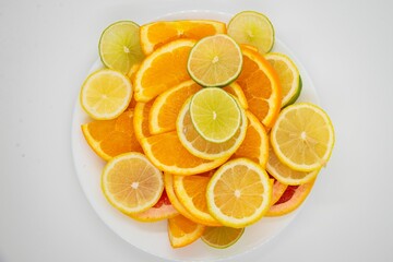 White plate with several slices of citrus fruits on a white background