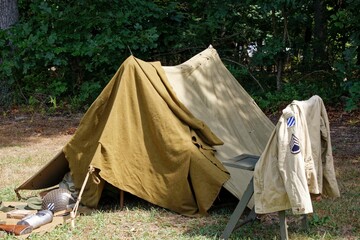 an army tent with a tan cloth on it next to trees
