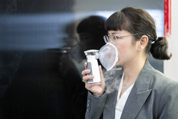 A woman holds a nebulizer for inhalation treatment