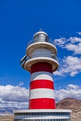 Faro de Arinaga lighthouse on the side of a hill with a blue sky in the background in Spain