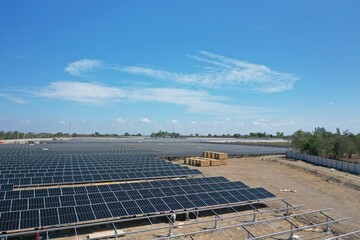 Aerial view of a large-scale solar farm with an array of black solar panels arranged in neat rows