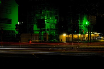 Vibrant green light illuminates a bustling urban street at night