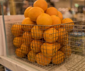 Closeup of fresh oranges in a basket at a store with a blurry background