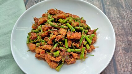 Stir fried crispy pork belly and yard long bean with ginger red curry paste, Authentic Thai food.