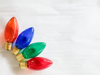 Red, blue, and green Christmas light bulbs on a white background with copy space