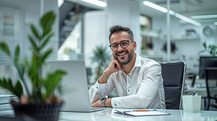jeune homme souriant dans un bureau en train de téléphoner assis devant son ordinateur