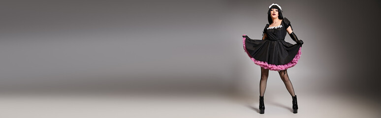 alluring female cosplayer in tempting maid costume looking at camera on gray background, banner