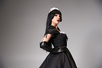 seductive sexy female cosplayer in tempting maid costume looking at camera on gray background