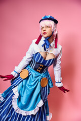 beautiful fashionable woman cosplaying cute anime character and looking away on pink backdrop